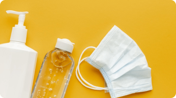A medical mask and bottle of water on a yellow background.